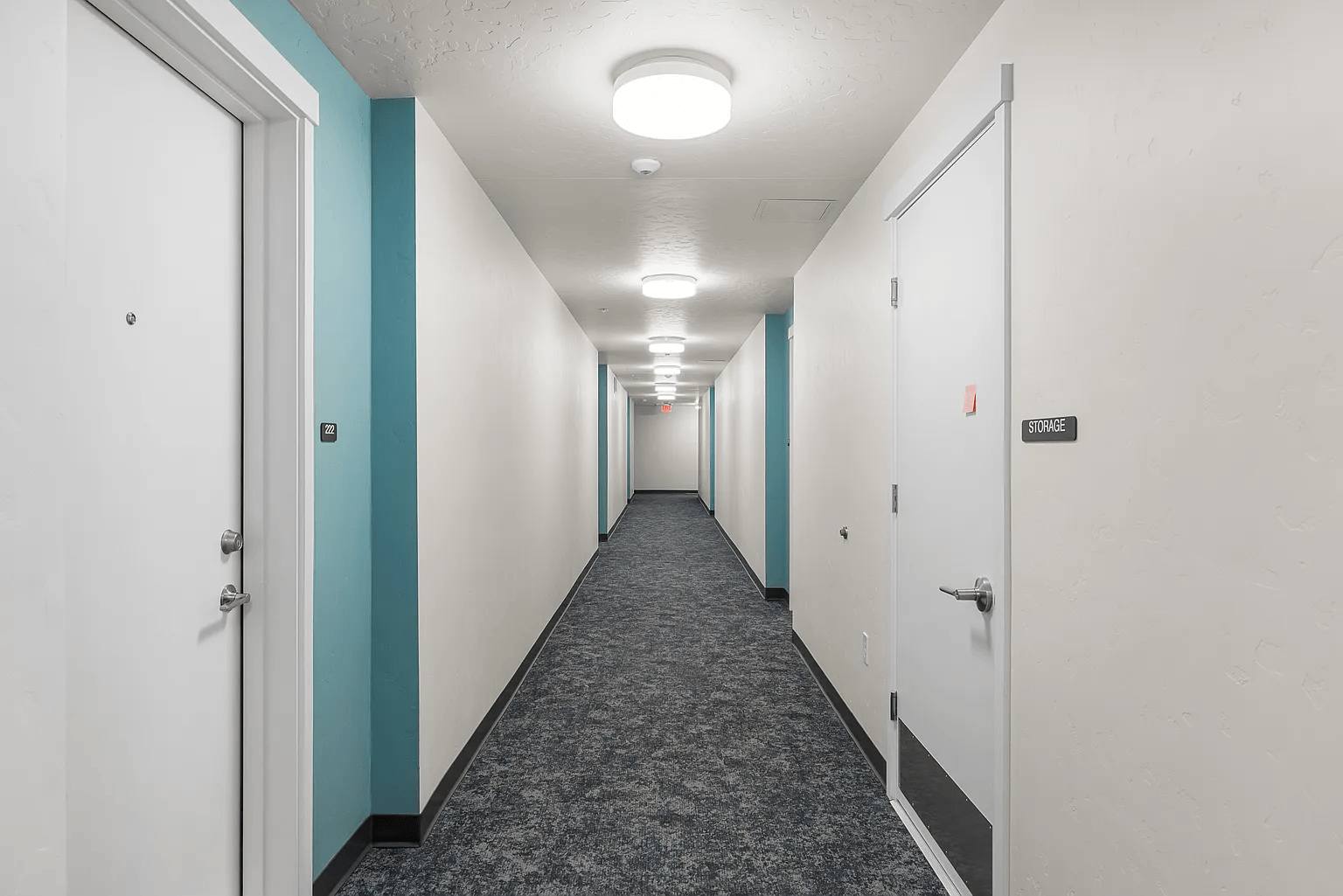 A long hallway with doors on both sides and a sign on the wall.